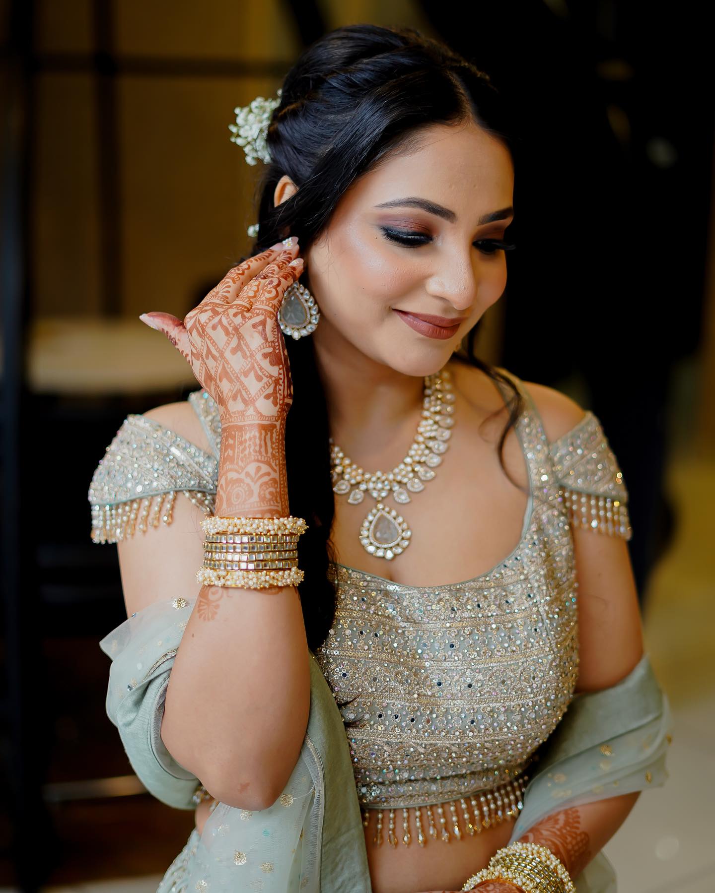 Bridal close-up with smoky eyes, fresh mehendi and a gajra-woven braid